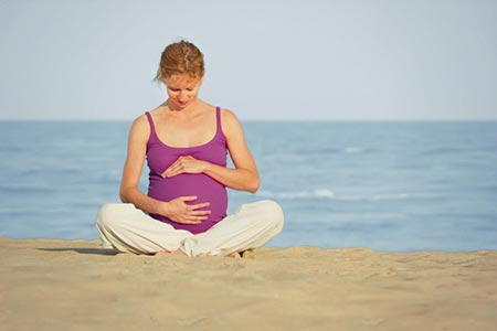 pregnant woman sitting on the beach
