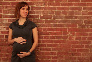 pregnant woman standing next to a building