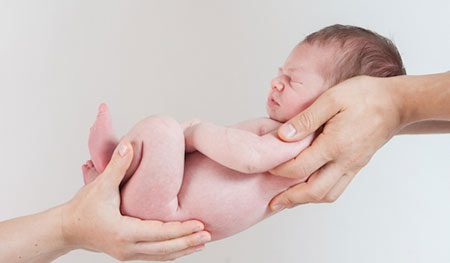 Close up of two adults holding a baby
