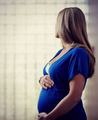 Pregnant woman cradling her belly and looking away from the camera