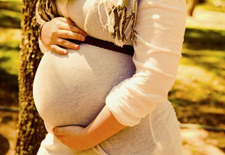 Close-up of a pregnant woman cradling her belly