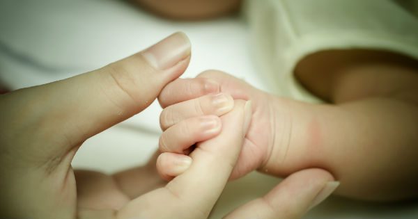 Mother holding her newborn baby's hand