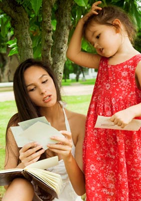Young mother and her daughter outside looking at photos