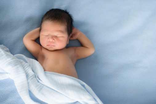 Asian baby boy sleeping on a blue blanket 