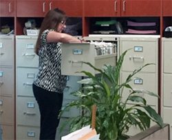 A woman retrieves a profile from a file cabinet