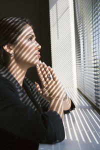 Woman leaning on windowsill praying