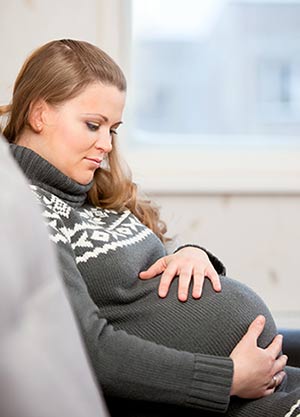 Pregnant woman in a sweater caressing her belly