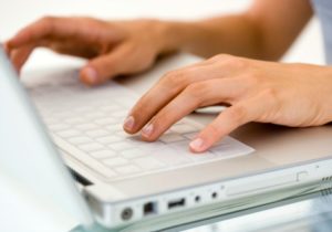 Close up of a woman's hands typing on a laptop
