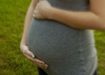 Close-up, cropped shot of a pregnant woman cradling her belly