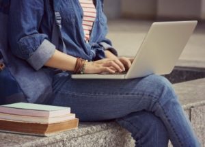 Cropped photo of a female student sitting down and using laptop