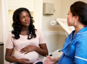 Pregnant black woman listens to her OB during a prenatal appointment