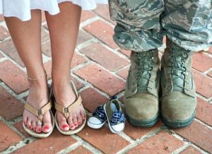 Military couple posing with baby shoes