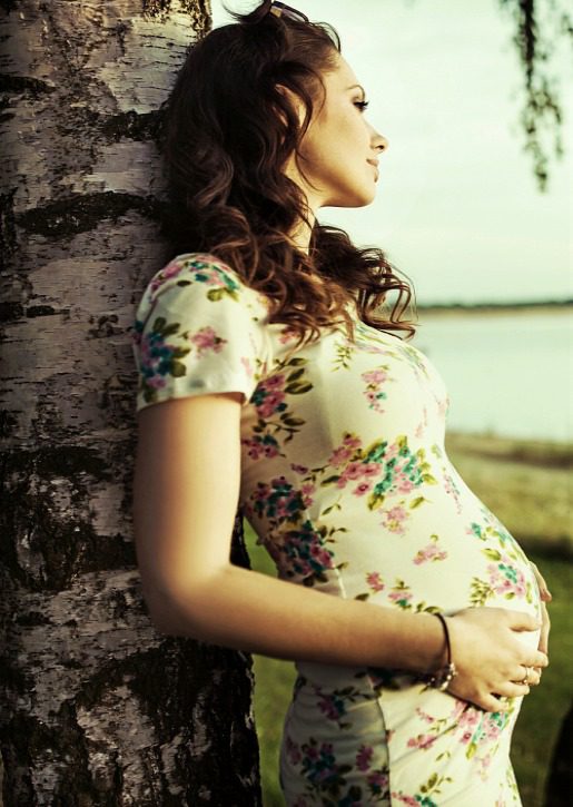 Pregnant women leaning on Birch Tree