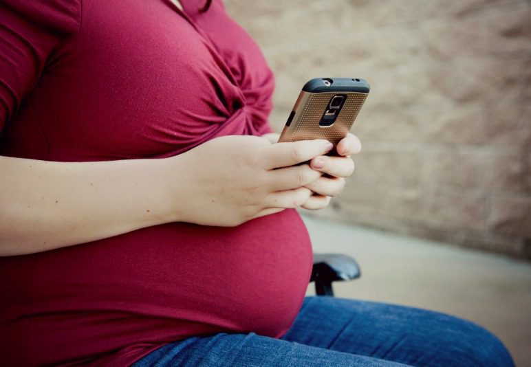 pregnant woman looking into adoption situations on her phone