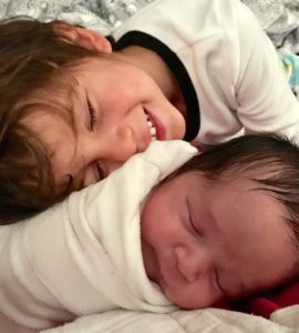 young boy snuggles with his newly adopted baby sibling