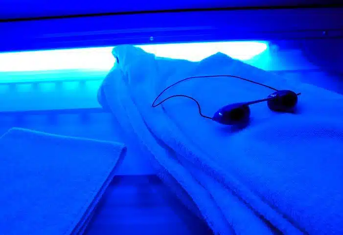 Empty tanning bed with goggles and a towel draped over it