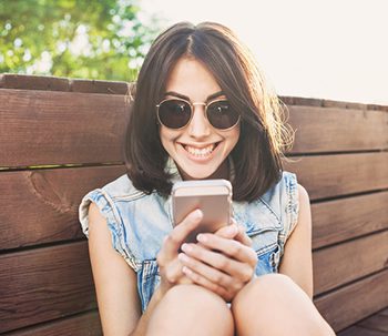 Young woman enjoys looking at message on phone from her child's adoptive family in an open adoption