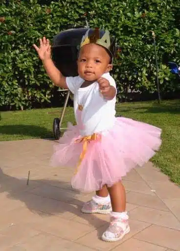 beautiful young girl reaches out for her adoptive parent taking her photo, this family followed all the steps in the adoption process to adopt their happy baby