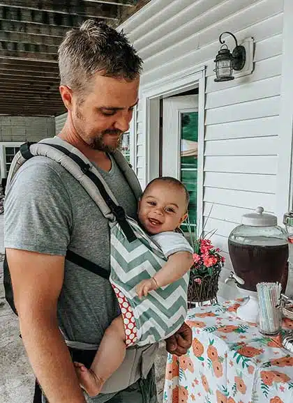 Father holding his priceless newly adopted son in a chest carrier