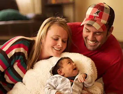 A happy adoptive family holding there new born adoptive child at home in a blanket