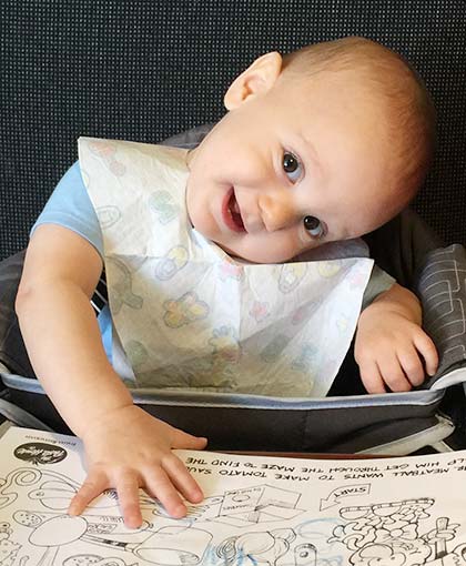 really cute baby looks sideways at camera from his high chair, his parents have medical release and health information for him from birth parents