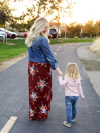 pregnant woman getting back in touch holds daughter's hand as they walk together
