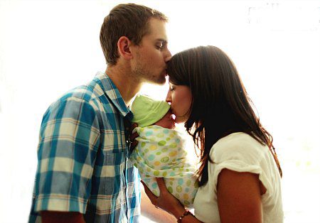 adoptive couple hold their new baby and give her kisses