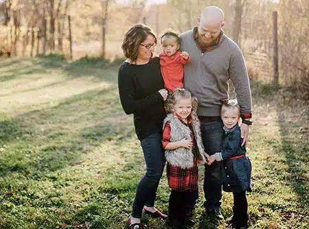 A Caucasian family of four celebrating the benefits of adoption in a park