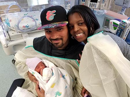African American married couple holding and seeing their adopted infant for the first time in the hospital 