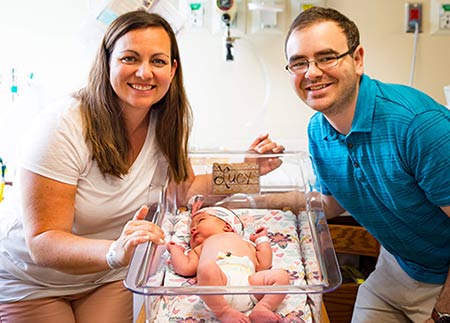 Adoptive parents make a hospital visit with their new baby in her basinet