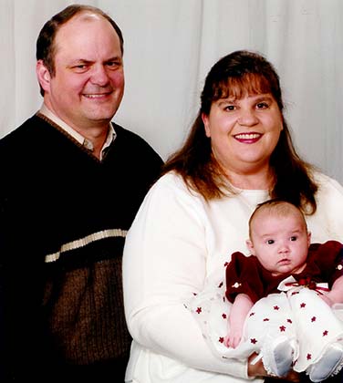 Adoptive parents hold new baby and smile at camera as they tell their Lifetime baby adoption story
