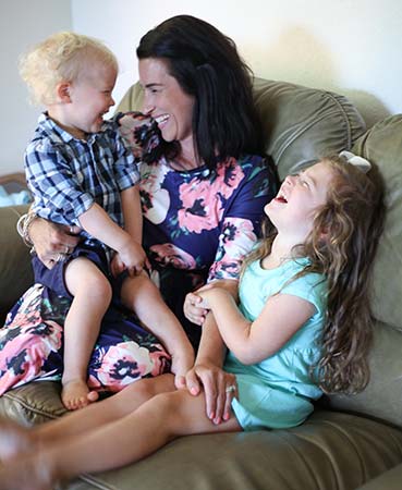 mother and her two adopted children laugh together on the couch
