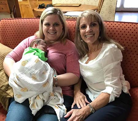 Mardie Caldwell, C.O.A.P., sits with a smiling new adoptive mom and her baby
