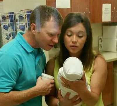 Adoptive couple look at their new born baby in the hospital with awe