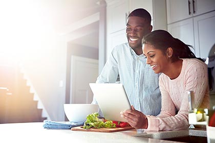 African American couple researching online adoption on their laptop in a kitchen