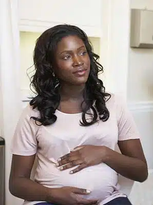 Africn American pregnant woman considering parenting or adoption as she listens to a podcast from the library discussing this topic