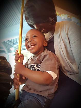 Mother rides carousel with her happy adopted son
