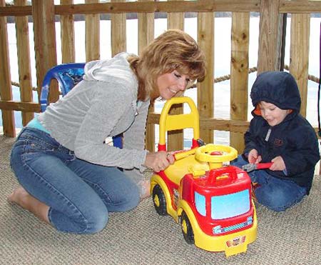 Adoptive mom plays with her son and his ride on fire truck on the deck