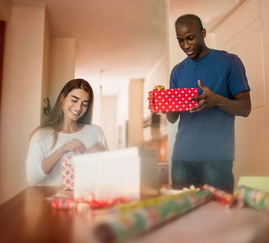 young hopeful biracial couple wrap gifts