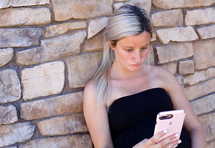 Pregnant woman looks at adoptive families on her phone