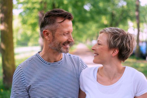 Hopeful adoptive couple in their 40s beaming at each other, not too old to adopt