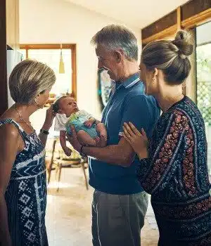 Adoptive grandparents admiring their new grandchild as his adoptive mother looks on