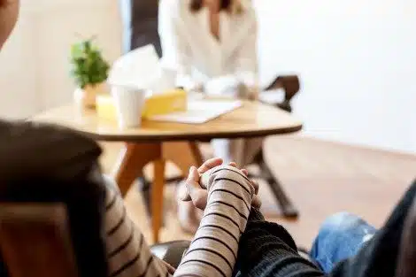 Cropped shot of a couple holding hands during couples therapy while the counselor looks on