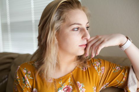 Young blonde woman in her living room, looking outside