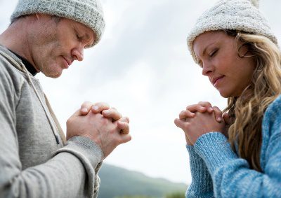 Married couple pause during a hike to pray together