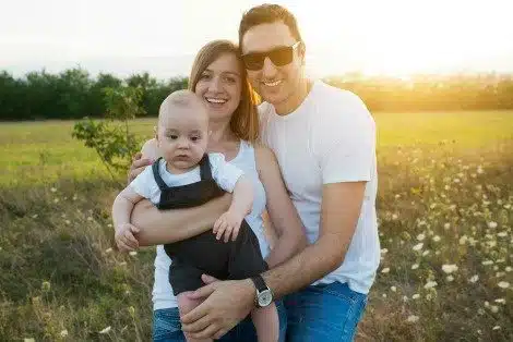 Happy couple in a field with their baby