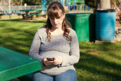 Woman searching on phone for how to give baby up for adoption