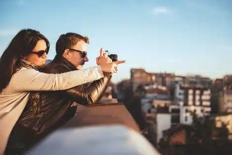 Couple wearing sunglasses take photos from the top of a building