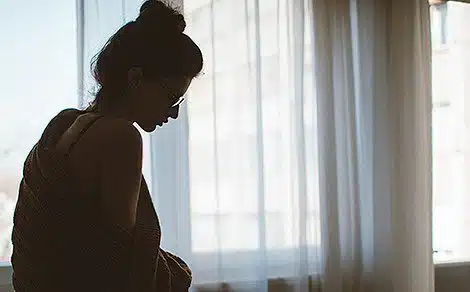 Silhouette of a woman wearing a bun with bright sun shining in from the window