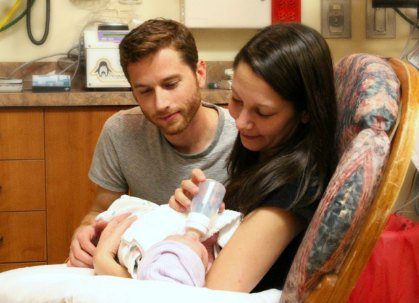 New adoptive parents carefully feeding their adopted newborn baby